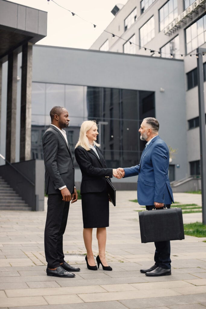 Business professionals shaking hands outside a modern commercial building, symbolizing successful real estate transactions and partnerships in Connecticut's commercial market.